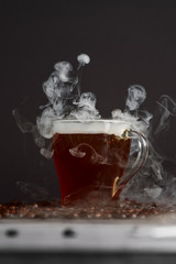 Hot coffee with steam effect on coffee beans, dark background