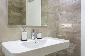 Soap and shampoo dispensers near Ceramic Water tap sink with faucet in expensive loft bathroom