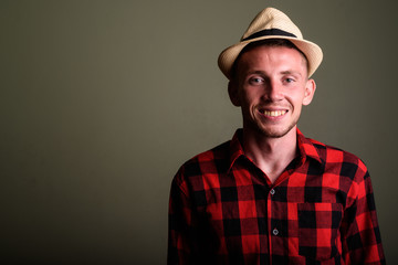 Young tourist man wearing hat and red checkered shirt against co