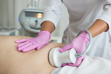 Closeup photo of fat man with big belly having cavitation procedure removing cellulite on abdomen...