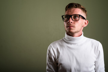 Fototapeta premium Young man wearing white turtleneck sweater against colored backg