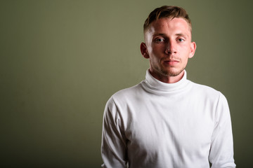 Fototapeta premium Young man wearing white turtleneck sweater against colored backg