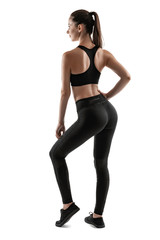 Fototapeta premium Brunette woman in black leggings, top and sneakers is posing isolated on white. Fitness, gym, healthy lifestyle concept. Full length.