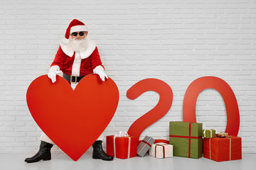 Santa Claus holding red paper heart while posing at camera