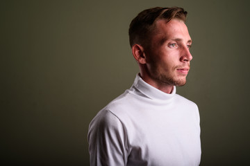 Fototapeta premium Young man wearing white turtleneck sweater against colored backg