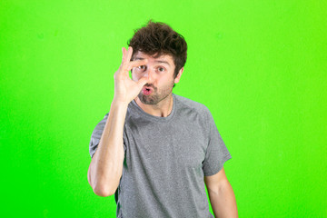 crazy young man making weird gestures over green background