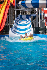 Happy family at the bottom of striped waterslide