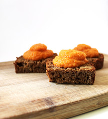 Toasted rye bread with vegetable caviar puree on a wooden cutting desk rustic style background
