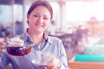 Waitress takes a cup with a tea kettle for the client at the restaurant. The concept of service and maintenance. Toning