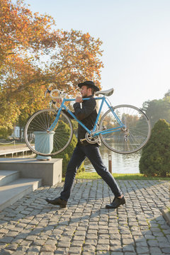 Man carrying vintage city bike up the stairs outdoor