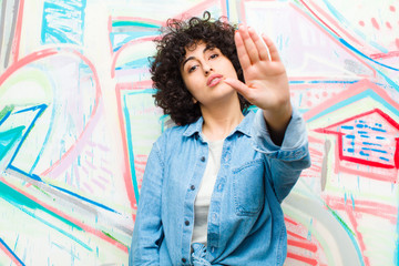 young pretty afro woman looking serious, stern, displeased and angry showing open palm making stop...