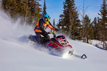 Fotobehang In deep snowdrift snowmobile rider make fast turn. Riding with fun in deep snow powder during backcountry tour. Extreme sport adventure, outdoor activity during winter holiday on ski mountain resort © Wlad Go