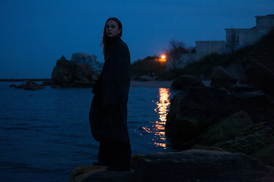 girl in a dark dress posing against the backdrop of the night sea