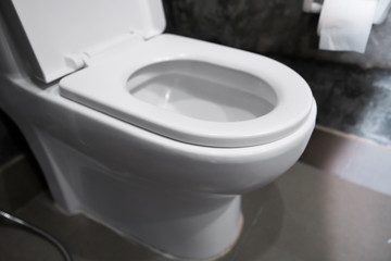 White hanging toilet seat on white toilet in the home bathroom with grey tiles in concrete style...