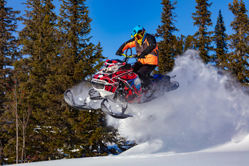 A man is riding snowmobile in mountains. Beautiful morning light. jump on a snow bike. pilot on a...