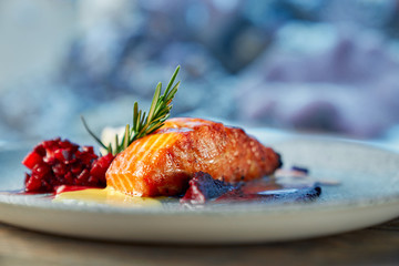 Closeup of piece of red salmon served with fruit garnish