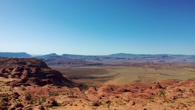Aerial-Flying over rugged desert sandstone cliffs to distant Warner Valley at Sand Hollow in the barren Utah desert