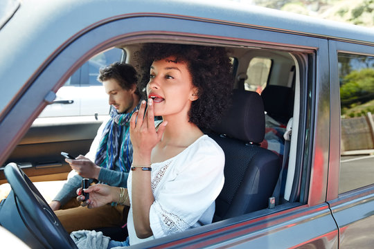 Young ethnic millennial woman putting on makeup in her car