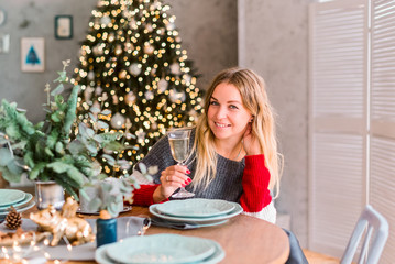 Smiling beautiful blonde with glass of chapmpan at the christmas tree