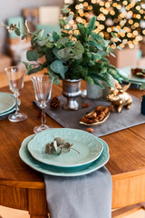 Christmas table with table setting with glass, pine corn and green