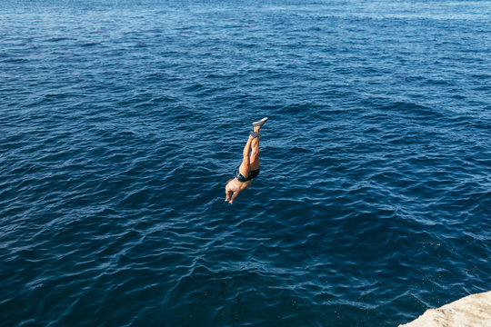 Man jumping from a rock in the sea