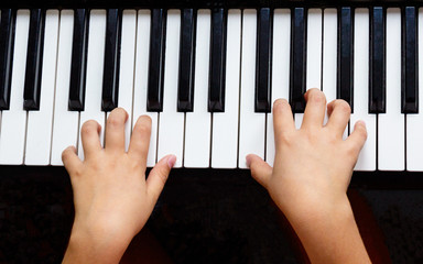 Closeup of the hands of a child playing the piano. Hands of a child playing the piano keyboard. A closeup image of the hands of a child playing on the pianoChild hands on the piano keyboard. Kid playi