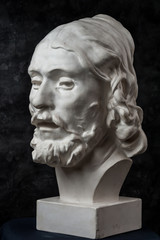 Gypsum copy of ancient statue John the Baptist head on dark textured background. Plaster sculpture...