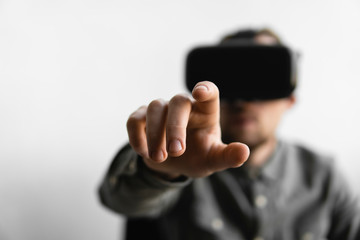 Young bearded man with virtual reality glasses trying to touch something or tap some thing in front of what he seeing. Modern technologies. The concept of future technology.