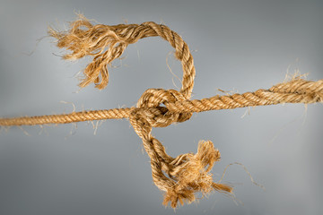 Rough ropes connected by large knot on gray background