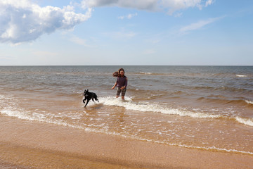 Girl and dog running in the water in Latvia