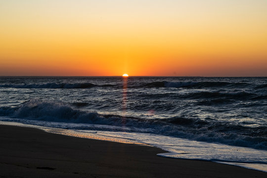 Sunrise over the Black sea, waves on the sandy beach.
