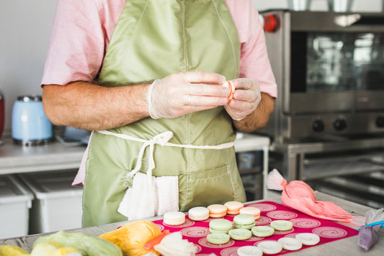 Man filling fresh baked macrons