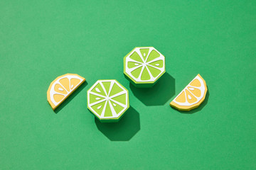 Handcraft lemon slices and lime halves on a green background wit
