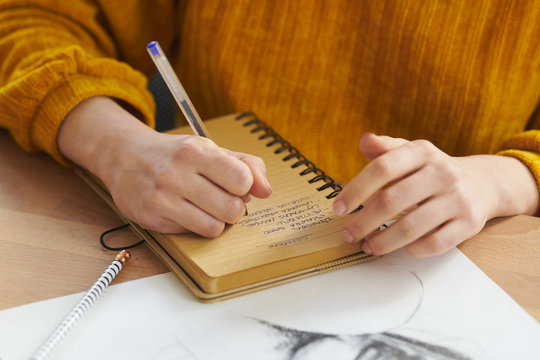 Crop woman writing list in notepad