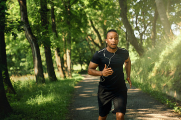 Athlete running and listening music in park.