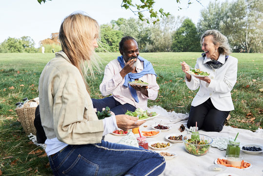 Senior friends eating healthy food picnic.