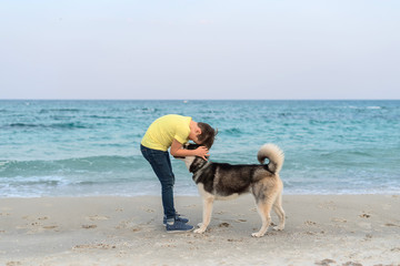 Boy and husky dog in collar on the beach