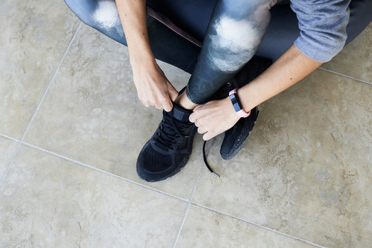 Fitnesswoman tying shoelaces at home.