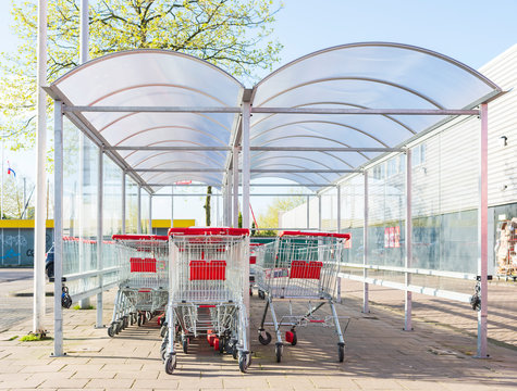 Supermarket shopping trolleys under awning in spring sunshine