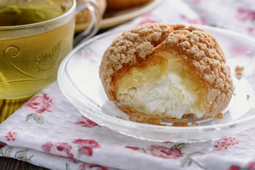Delicious lush bun with creamy filled and a cup of tea nearby cooked for breakfast
