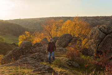 Old gray-haired man with a beard on the background of the gorge and stones