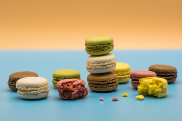 delicious macarons full and bitten and crumbs arranged on colored background