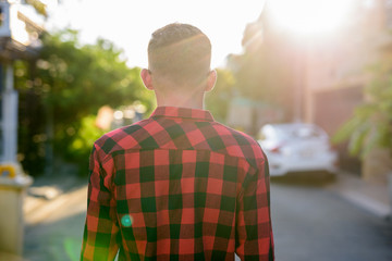 Fototapeta premium Young man wearing red checkered shirt in the streets outdoors