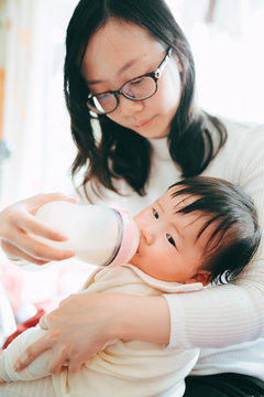 Asian mother feeds a baby girl to drink milk