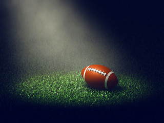 American football game ball on grass lit by spotlight, Gridiron stadium