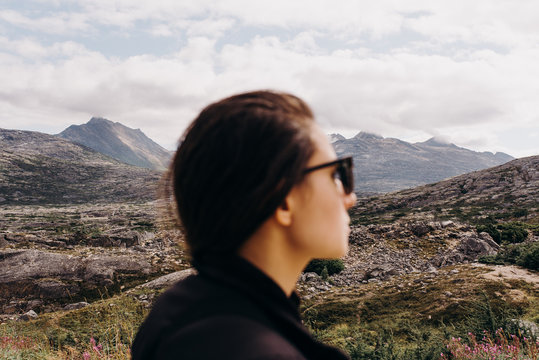 Young adult woman with sunglasses in front of an alaskan landscape