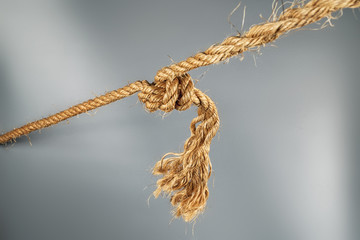Rough strong ropes connected by large knot on gray background