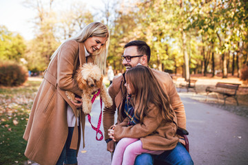 Disabled father in wheelchair enjoying with his daughter and wife outdoors in autumn park.