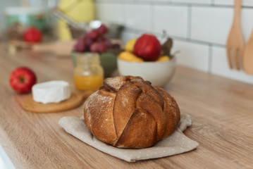 Freshly baked bread on napkin on the kitchen table, cheese and fruit, healthy breakfast