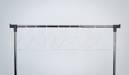 empty white metal hangers hang on a chrome bar, white background